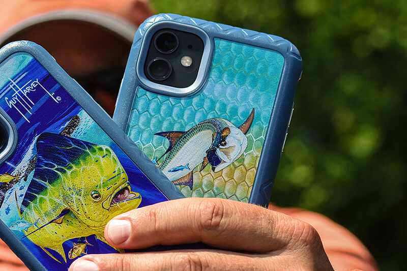 Hand holding two cell phones with covers designed by Guy Harvey, printed on a Roland DG VersaUV LEF2 printer